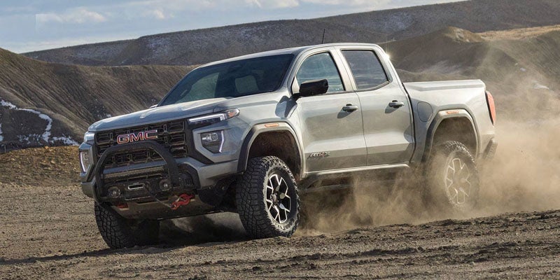 2026 GMC Canyon mid-size pickup truck driving on a rugged off-road trail