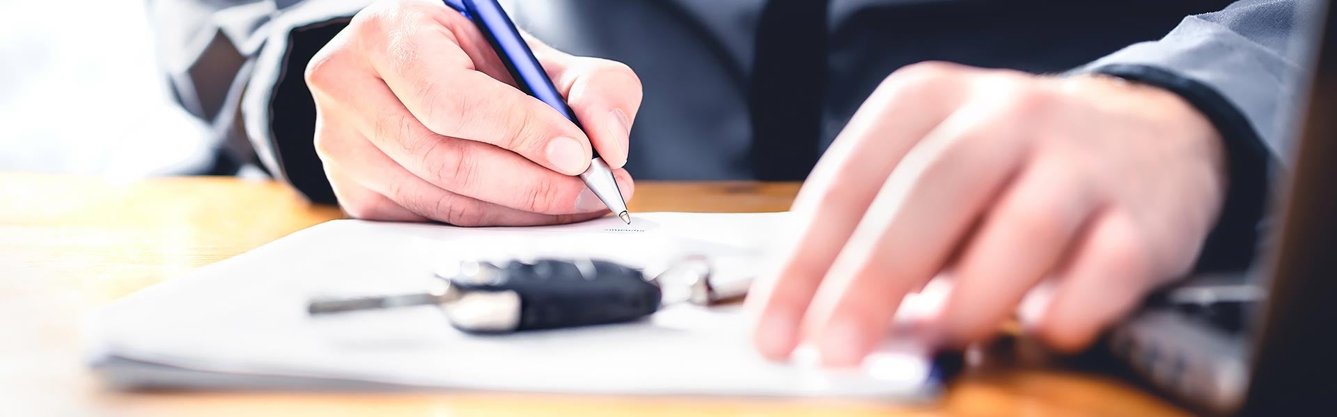 Person signing car finance paperwork at a dealership